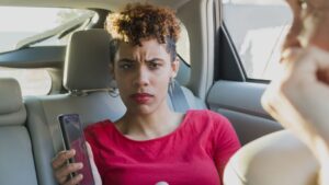 This is a passenger in a vehicle holding a smartphone. She looks angry. 