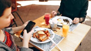 Food, Phone and Etiquette. A diner pulls out their phone while eating a meal.